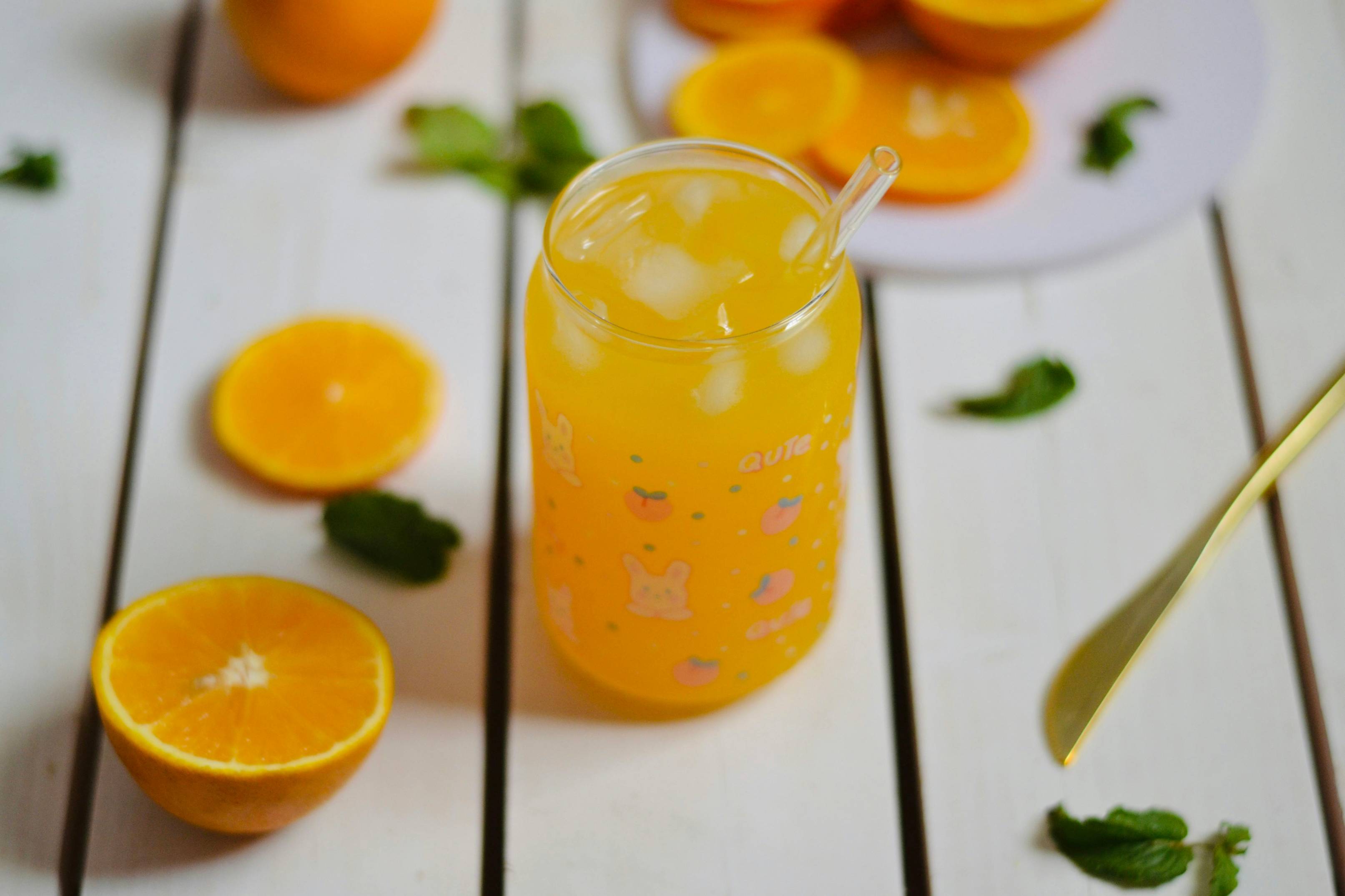 A glass filled with orange juice next to sliced oranges